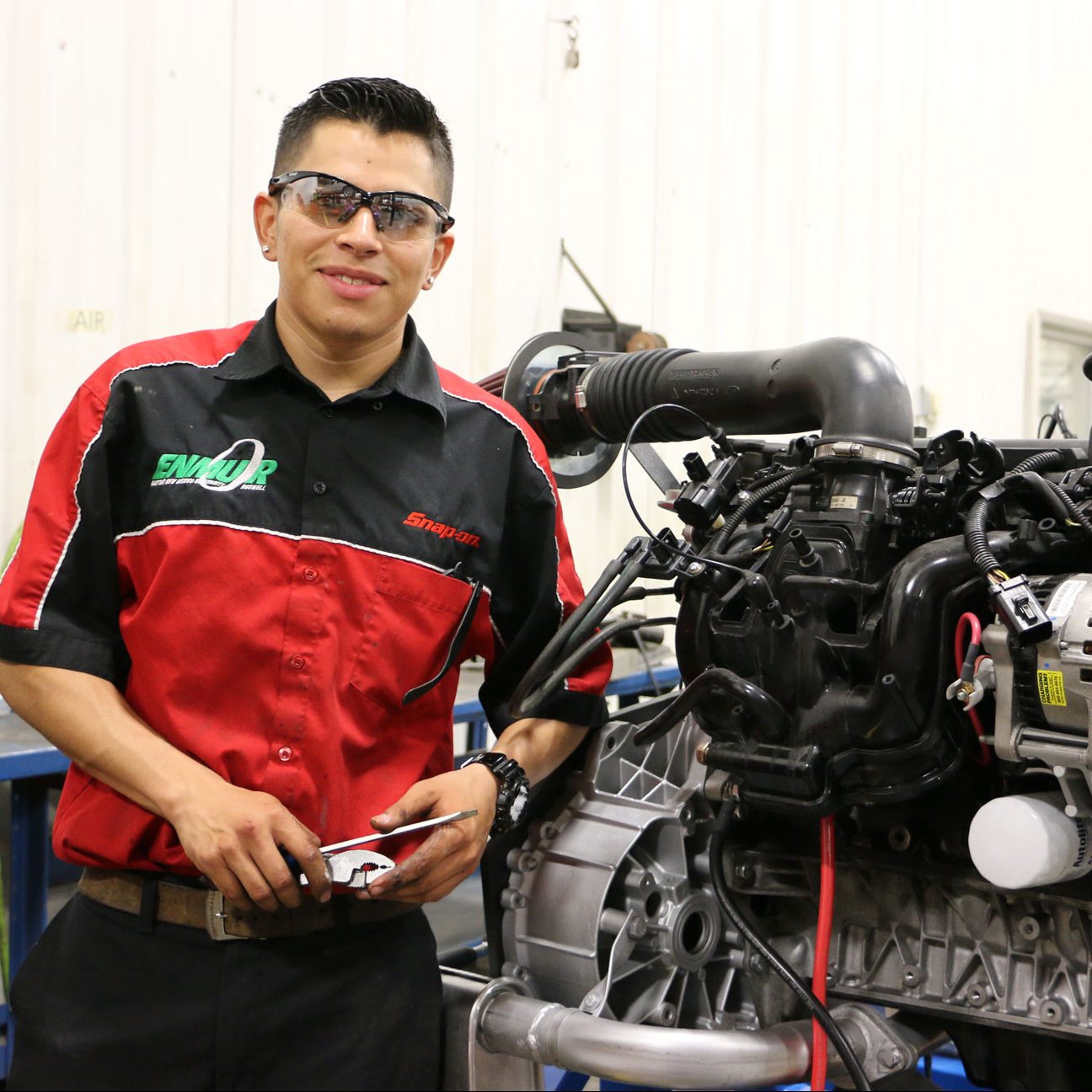 An automotive student of the Eastern New Mexico University Roswell campus poses with an engine