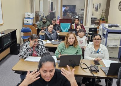 A classroom of about 12 students are learning basic computer skills