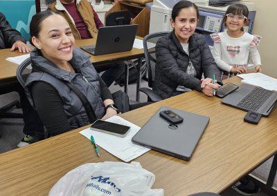 Three students participating in the Project C-3PO basic computer literacy course show off their new laptops