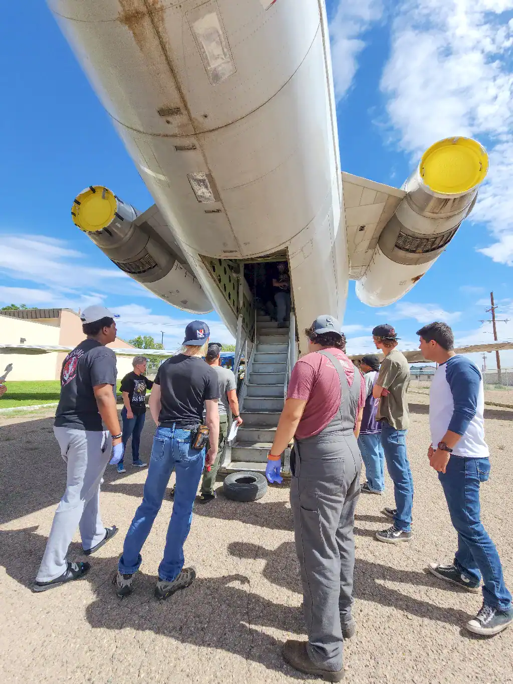 Aviation Maintenance students are standing at the rear entrance of a cargo jet facing the stairs leading up to the loading bay.