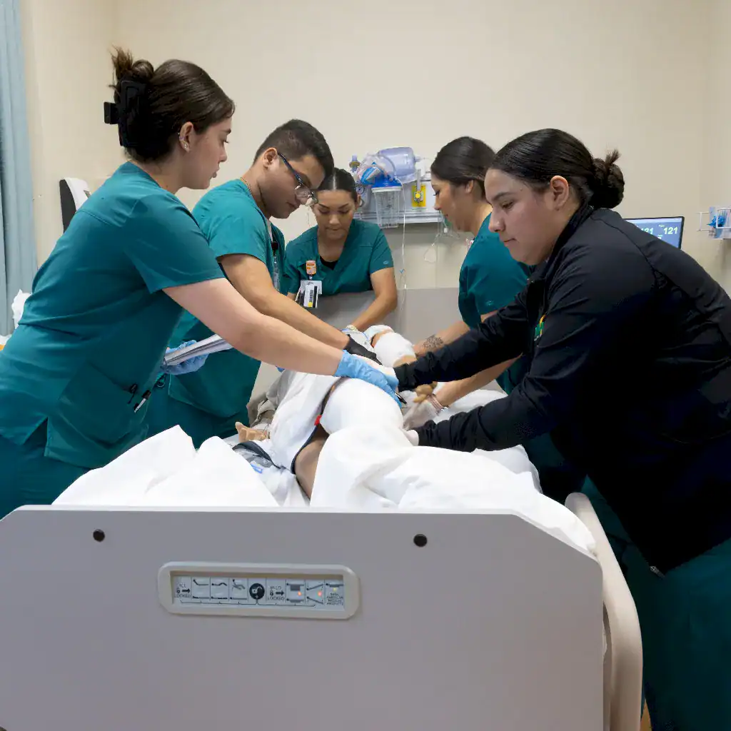 Nursing students at ENMU-Roswell cooperate to rotate a patient who is lying prone on a hospital bed.